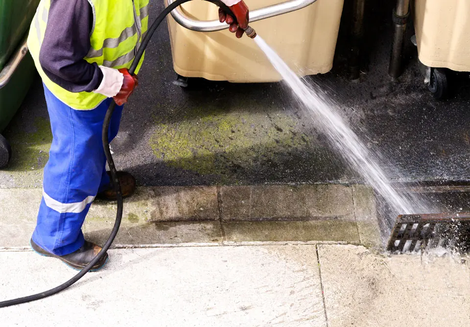 A person using a hose to clean the floor.