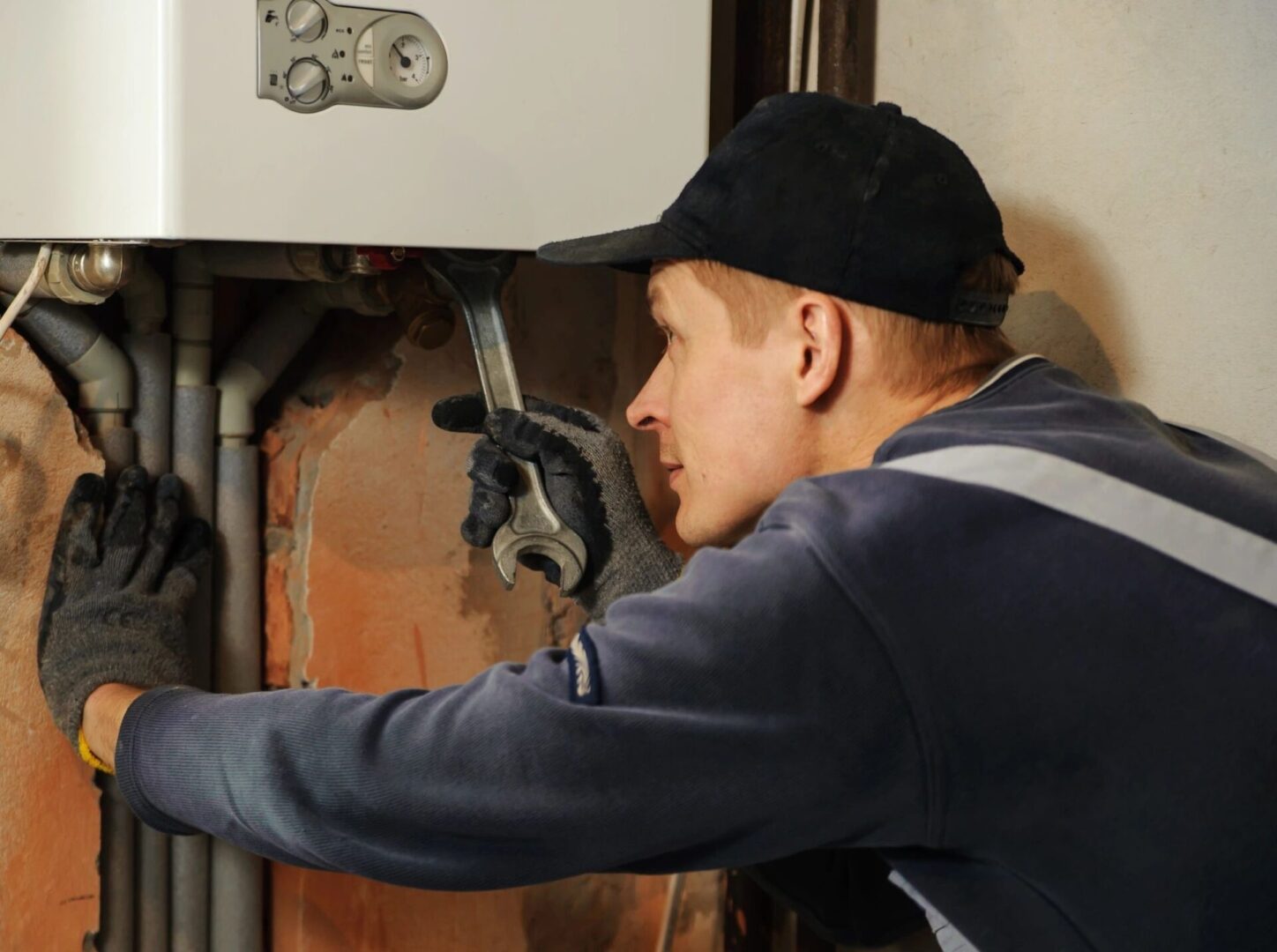 A man in black hat and jacket fixing a wall.