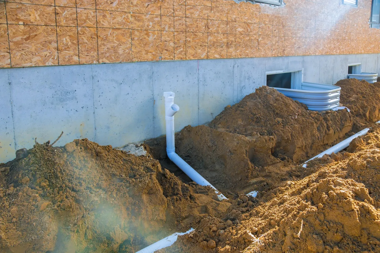 A view of a house with dirt and pipes.