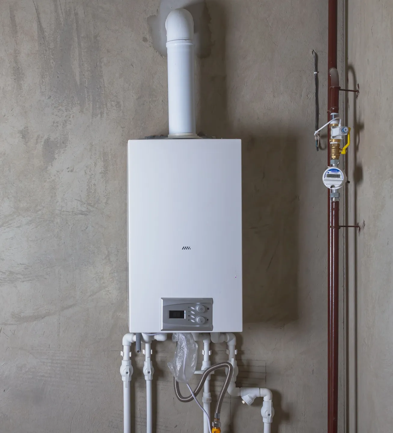 A white gas water heater mounted to the side of a wall.