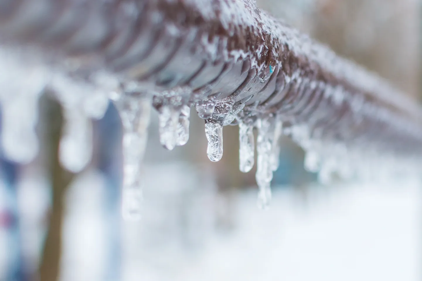 A close up of icicles hanging from the side of a pipe.