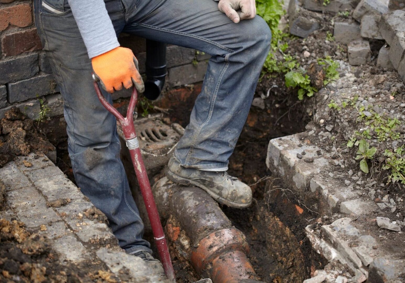 A person with an orange glove is digging a hole.